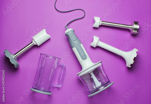 Electric hand blender with nozzles on a purple background. Top view, Flat lay