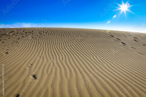 Summer background of sand on beach and blue sky with sun light. Free space for your decoration. 