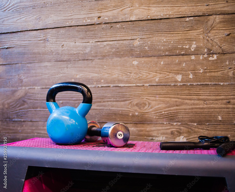 Functional training concept. Kettlebell, dumbbell, jump rope stand on a  fitness step platform against the wooden wall background. Copy space Stock  Photo | Adobe Stock