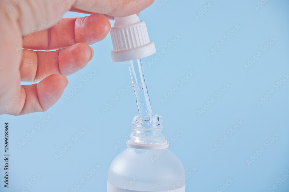 Pipette with liquid. A drop of dripping in a clear bottle. Female hand holding a dropper with liquid. Pipette with liquid. A drop of dripping in a clear bottle. Female hand holding a dropper with liquid.