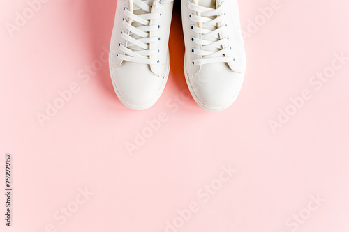 White female sneakers on pink background. Flat lay, top view minimal background. Fashion blog or magazine concept.