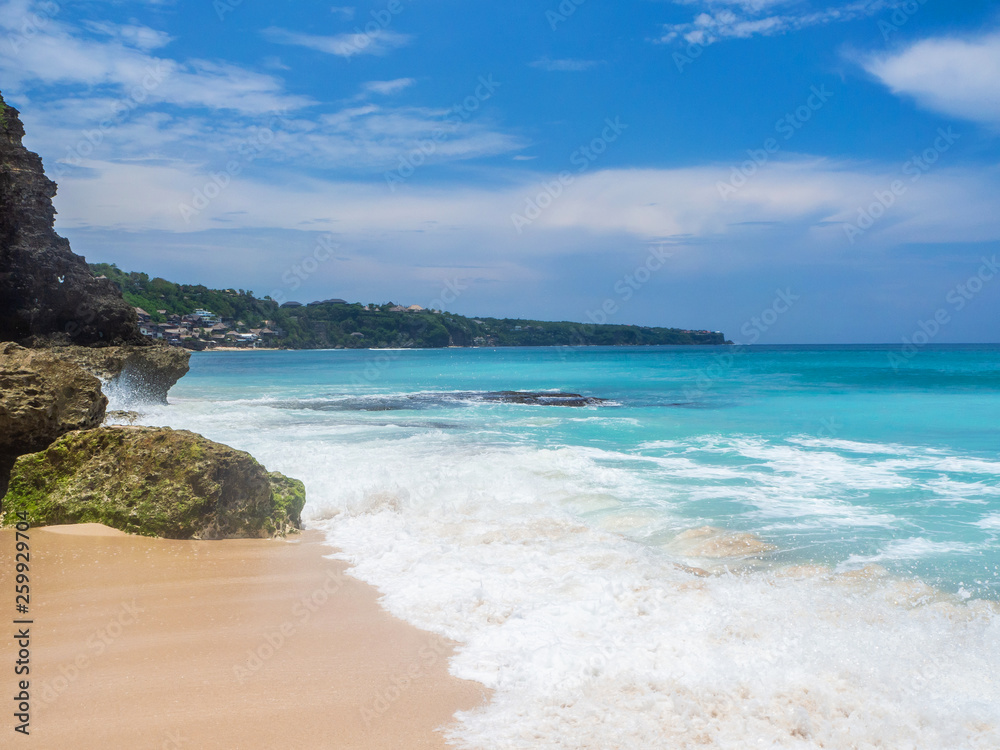 Obraz premium Turkusowe fale rozbijają się o kamienie z rozpryskami. Bali.