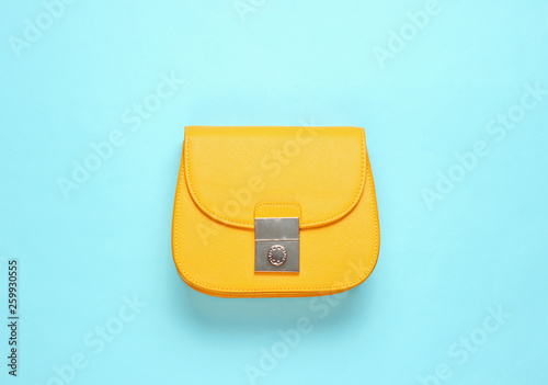 Yellow leather mini bag on blue background. Minimalism fashion concept. Top view photo