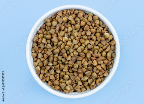 buckwheat in a plate on top, on a blue background, copy space