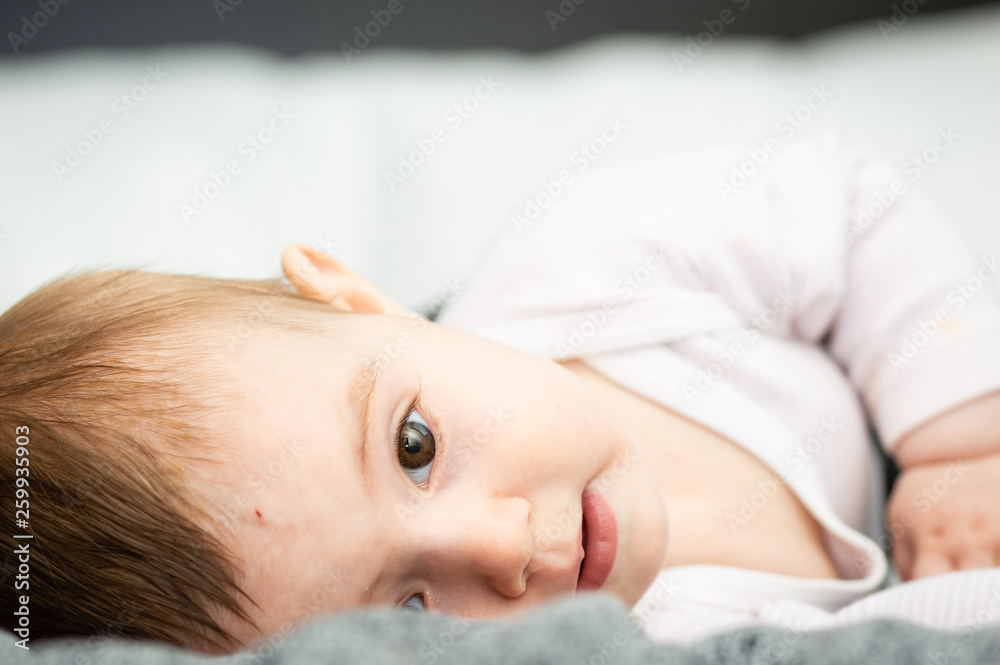 adorable blond baby lying on back on white bed adorable blond baby lying on back on white bed