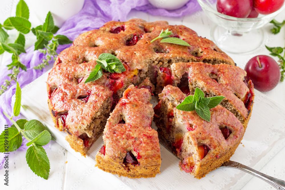 Delicious dessert plum pie, sweet delicious holiday plums cake with nuts on the white kitchen table. Delicious dessert plum pie, sweet delicious holiday plums cake with nuts on the white kitchen table.