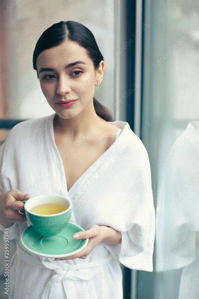 Waist up of thoughtful woman standing with cup of tea Waist up of thoughtful woman standing with cup of tea
