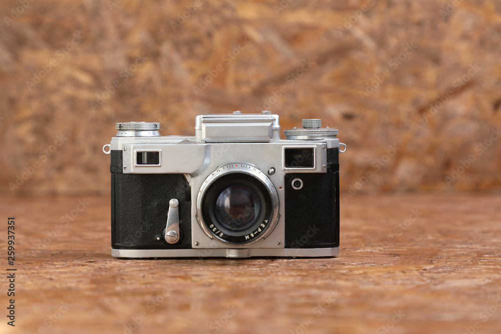 Old vintage film camera on brown textured background .