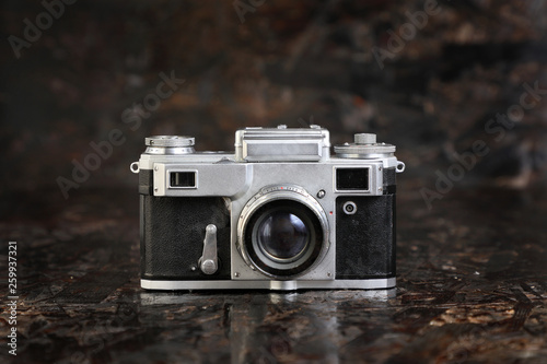  Old vintage film camera on brown dark texture background .