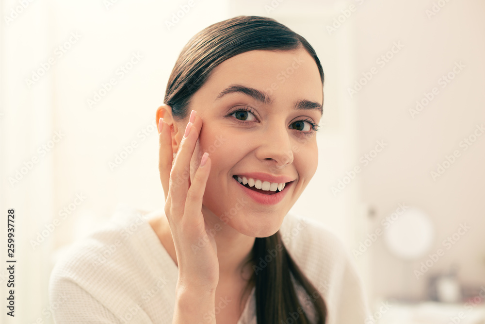 Positive woman smiling and touching skin on her temple Positive woman smiling and touching skin on her temple