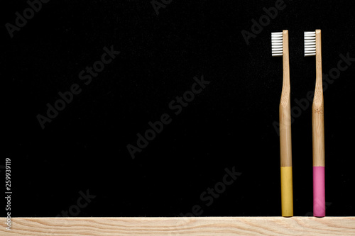 yellow and pink colour Bamboo toothbrushes on a slate background. Place for text.