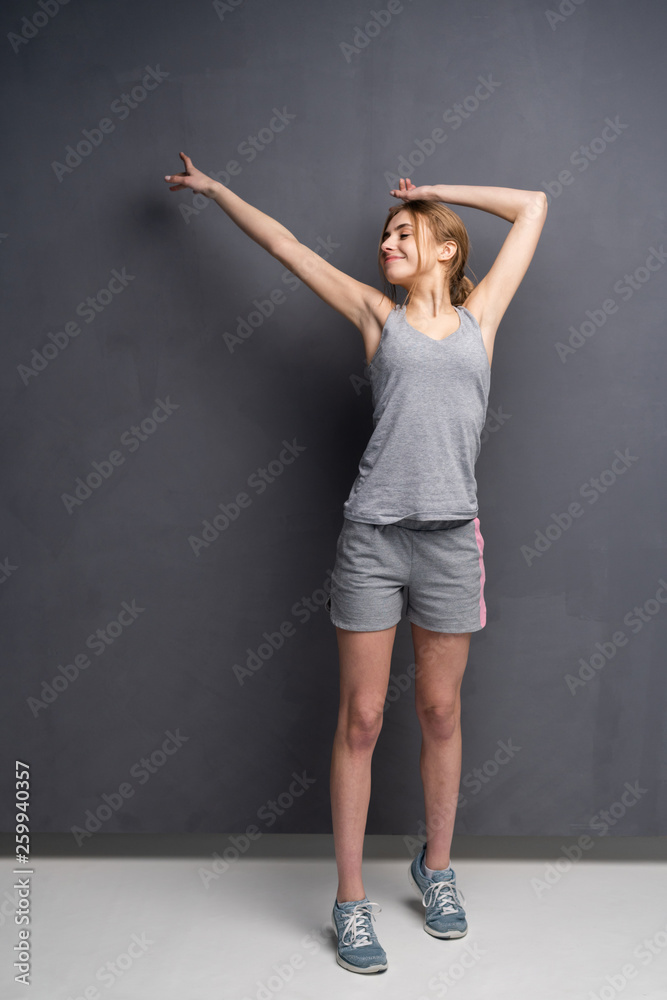 fitness woman. Young sporty Caucasian female model isolated on gray background in full body.
