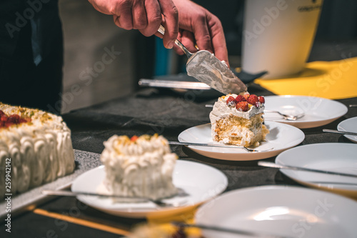 Strawberry and cream birthday cake served by the waiter in ceramic dishes