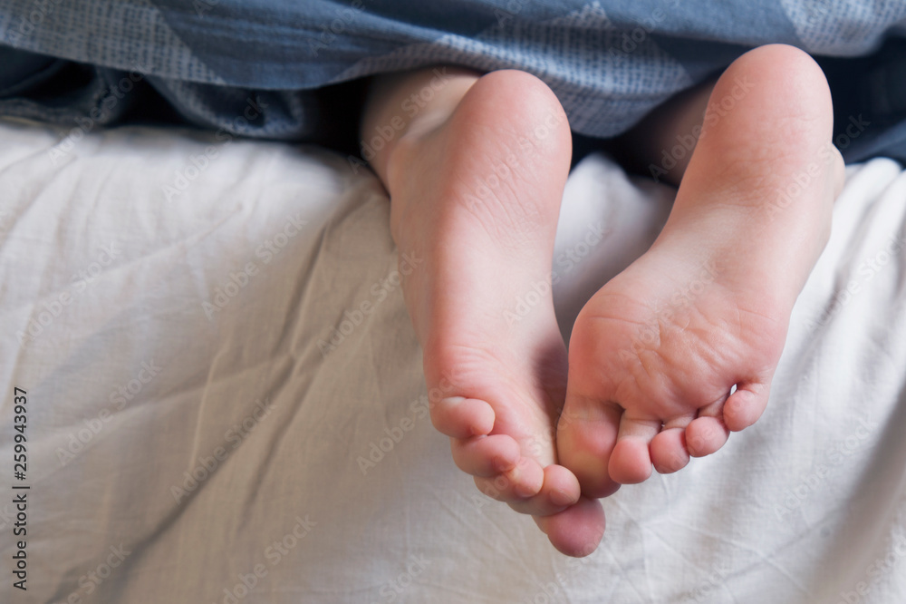 Beautiful groomed bare feet under a blanket as symbol of sleep, rest and relax. Beautiful groomed bare feet under a blanket as symbol of sleep, rest and relax.