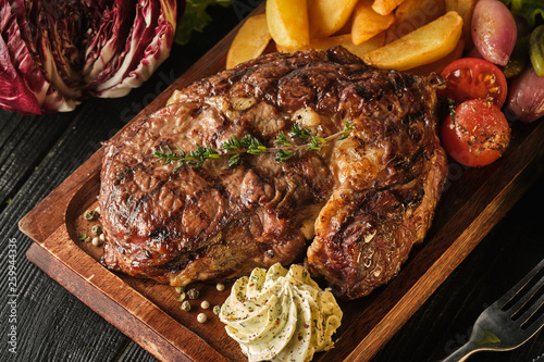 Ribeye steak with potatoes, onions and baked cherry tomatoes. Juicy steak with flavored butter photo