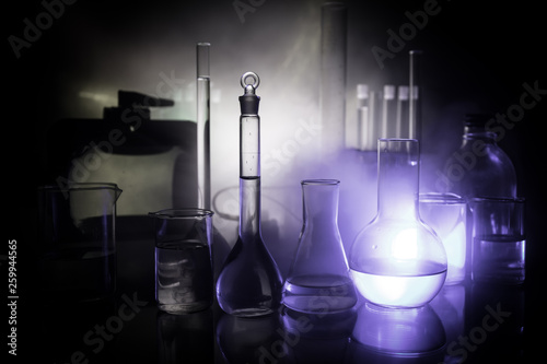 Pharmacy and chemistry theme. Test glass flask with solution in research laboratory. Science and medical background. Laboratory test tubes on dark toned background