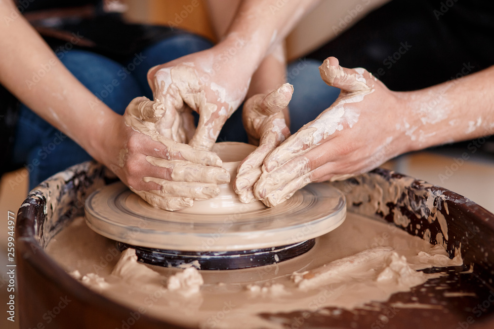 happy family on a creative joint vacation. romantic couple in love working together on potter wheel and sculpting clay pot