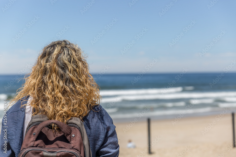 Fototapeta premium A tourist woman, placidly observes a beach on a sunny day