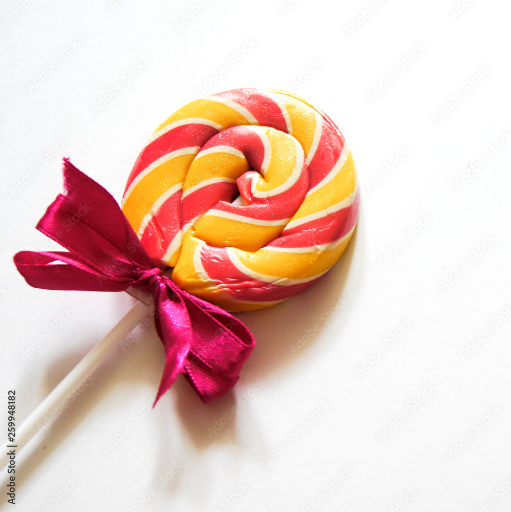Top view of sweet multicolor yellow-pink lollipop on a white background. Copy space Top view of sweet multicolor yellow-pink lollipop on a white background. Copy space