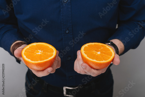 Handsome man in dark blue shrt holding in hands two halves of grapfruit, citrus concept photo