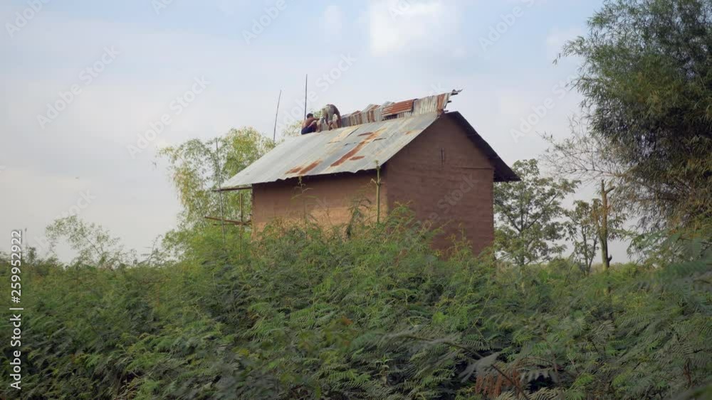 men repairing a roof at the top the tobacco barn 