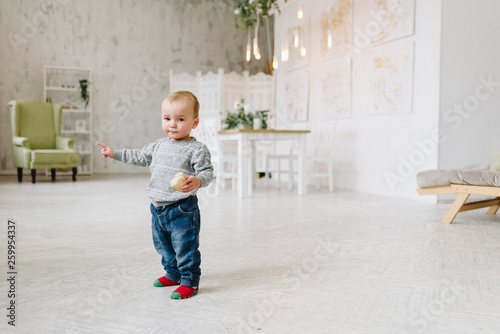 Wallpaper Mural Adorable caucasian toddler boy standing holding a snack. Kid is wearing jeans and a sweater. First steps. Torontodigital.ca
