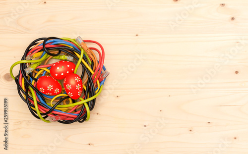 Easter eggs and nest of internet cables on wooden board