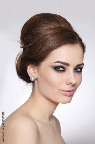 Vintage style portrait of young beautiful woman with fancy hair bun and smoky eye makeup