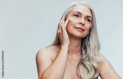 Senior woman putting on anti aging cream photo