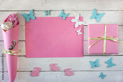 Różowo - białe wiosenne tło z zajączkami, motylkami, kwiatami i pudełkiem przewiązanym wstążką