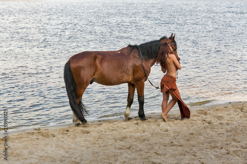 horse and young beautiful naked Amazon woman on river sand beach