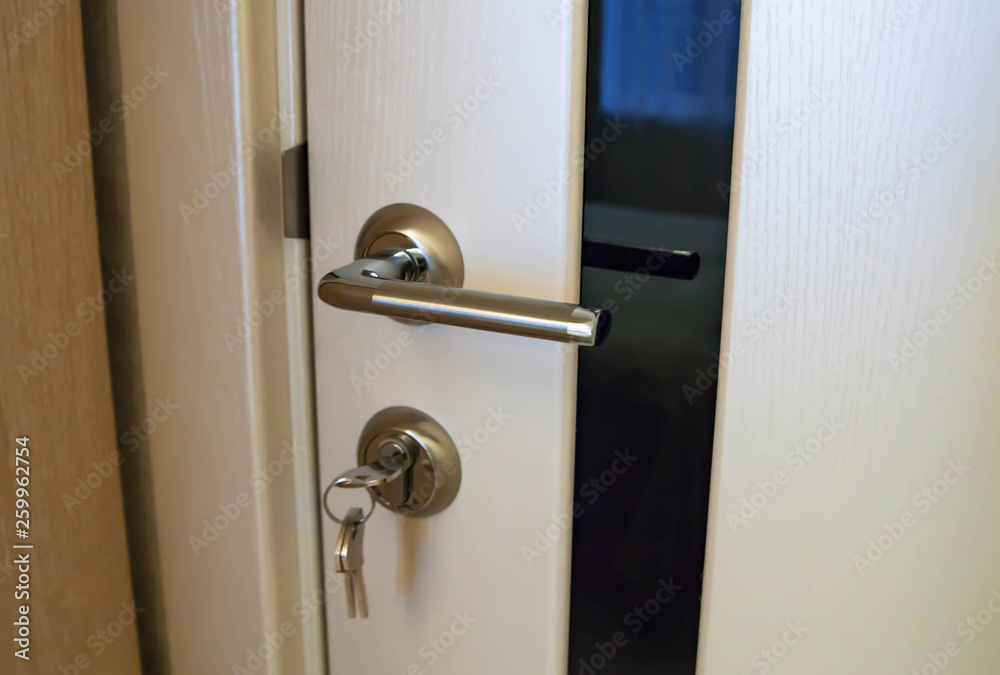 Metal door handle and keys close-up. white door with black glass Metal door handle and keys close-up. white door with black glass