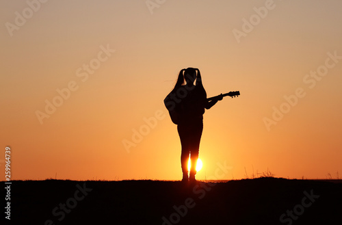 Silhouette of a guitar player at sunset, girl guitarist, silhouette of a guitar, music