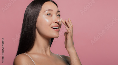 Canvas Print Youthful female model applying moisturizer
