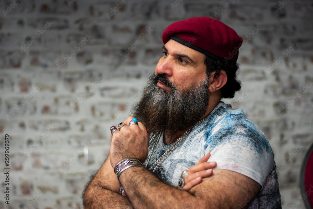  Ein Mann mit Bart, rotem Hut und Ringen aus Edelsteinen, Ketten und Accessoires