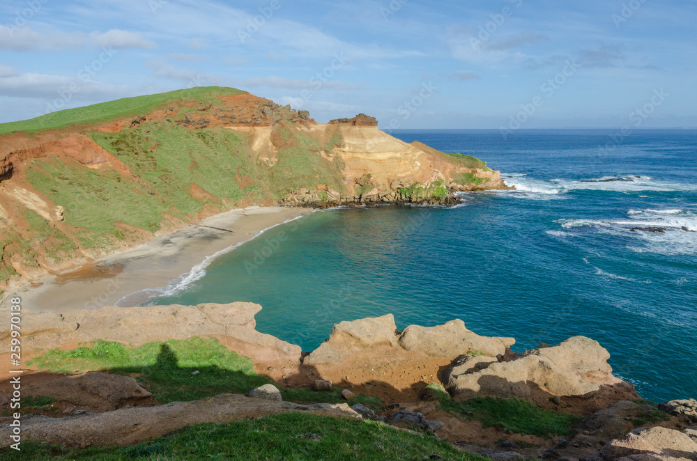 Elevated, view of a bay with eroded, red, sandstone cliffs in the Chatham islands, New Zealand.