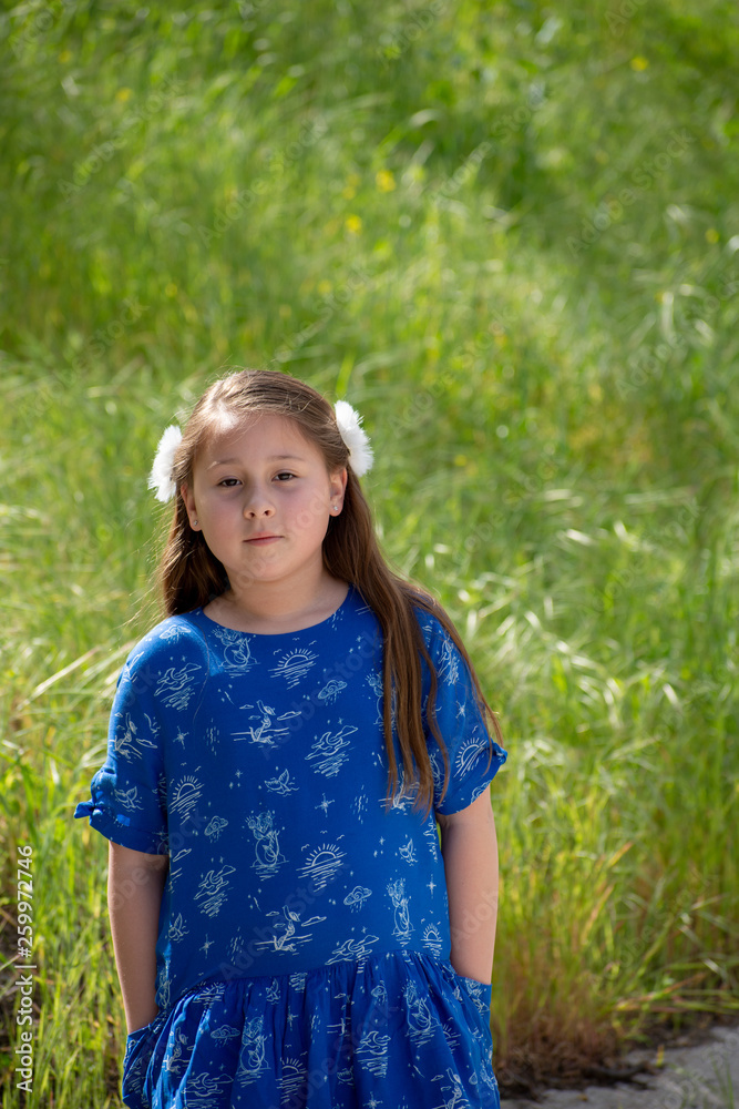Serious and Thoughtful Little Girl in Blue Dress in front of golden field at Park Serious and Thoughtful Little Girl in Blue Dress in front of golden field at Park