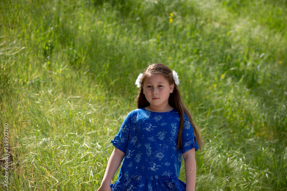 Serious and Thoughtful Little Girl in Blue Dress in front of golden field at Park Serious and Thoughtful Little Girl in Blue Dress in front of golden field at Park