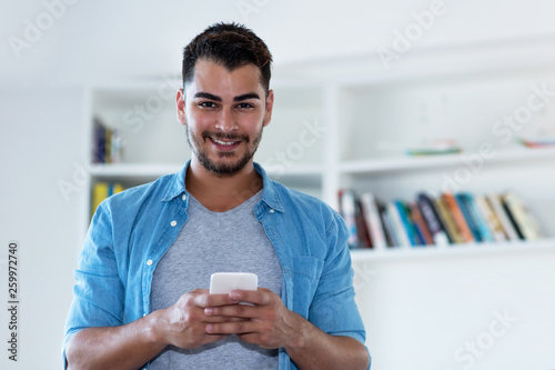 Mexican hipster man with beard sending message with phone