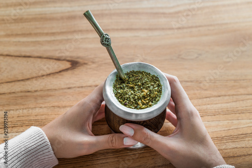 Young woman drinking traditional Argentinian yerba mate tea from a calabash gourd with bombilla stick 
