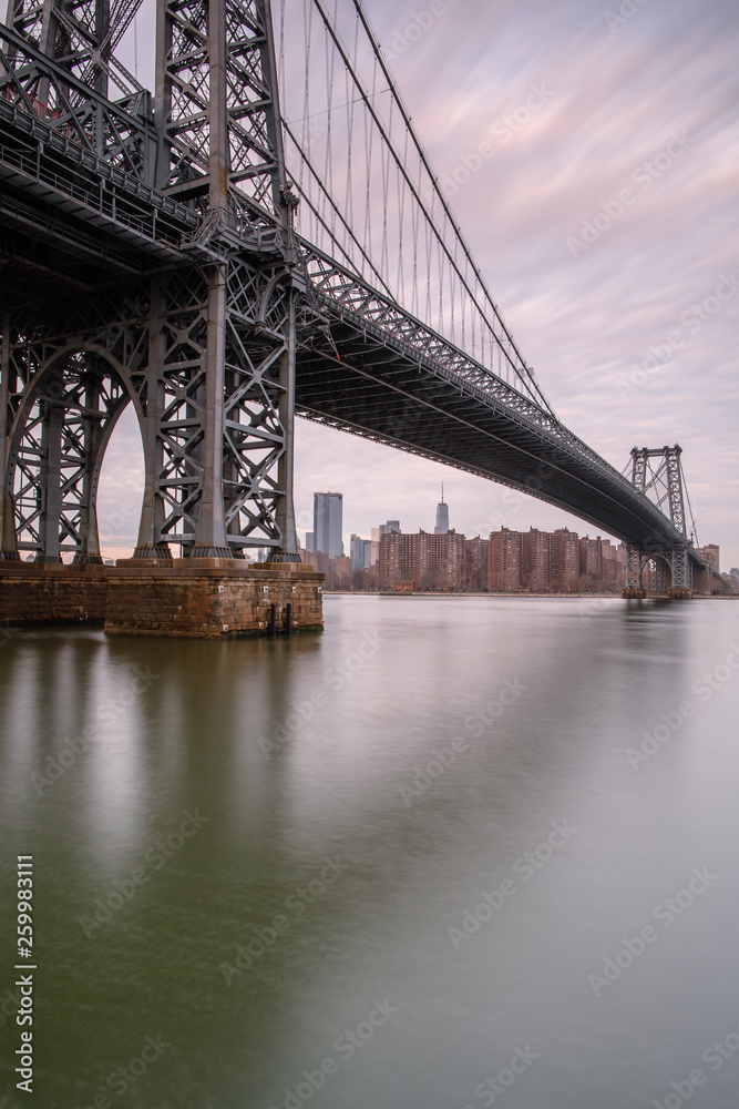 Williamsburg bridge from east river at sunrise with long exposure