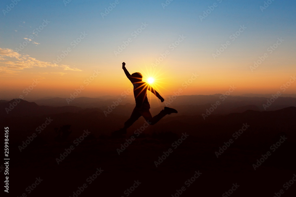 People jump on top of the mountain at sunset.