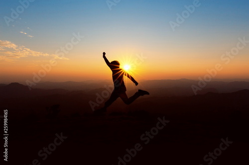 People jump on top of the mountain at sunset.