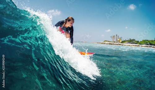 Happy lady surfer rides the tropical wave at sunny day