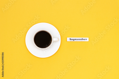 Cup of coffee and text September on yellow background