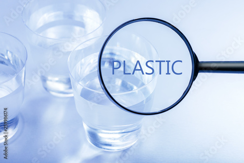 Plastic cup with water. Environmental problem concept. To consider problem in magnifier.