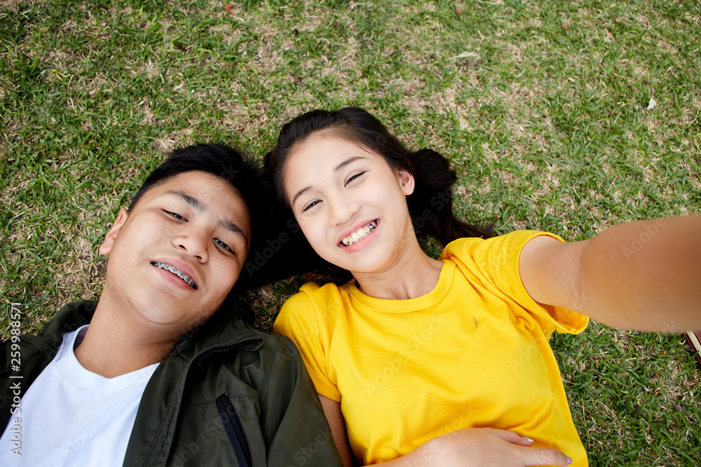 Obraz premium Teenagers with books lying on green grass