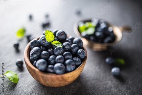 Wooden bowl full of fresh blueberries with herbs
