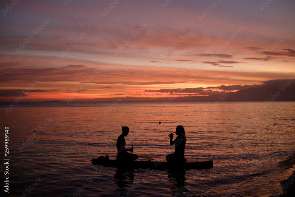 Two girls on a paddleboard during sunset