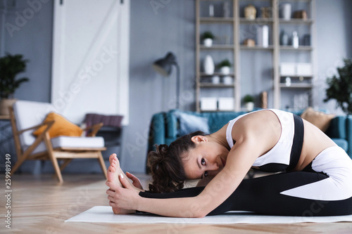 Young beautiful woman doing stretching exercises in the living room at home.